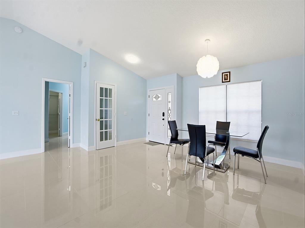 A dining area with light blue walls, tile flooring, a glass table, and four chairs — 14712 EAGLES CROSSING DRIVE, ORLANDO, FL