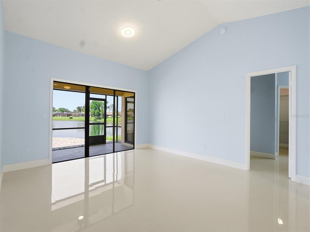 A bright room with light blue walls, tile flooring, and sliding doors opening to a lake — 14712 EAGLES CROSSING DRIVE, ORLANDO, FL