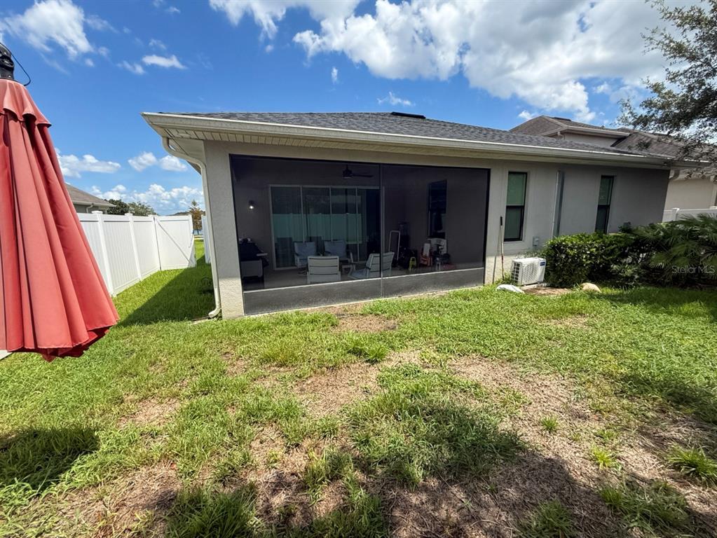 A view of a house exterior featuring a screened-in patio and a grassy backyard — 2524 FONTAINE DRIVE, KISSIMMEE, FL