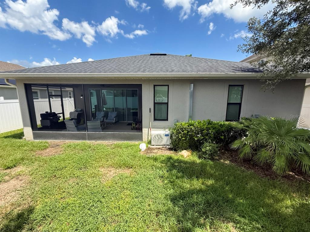 The rear exterior of a house features a screened-in patio, two windows, and an AC unit — 2524 FONTAINE DRIVE, KISSIMMEE, FL