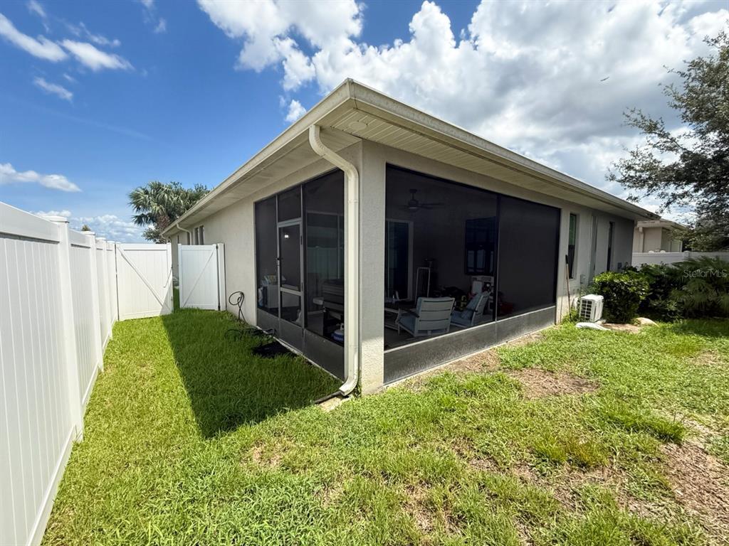 A screened-in patio attached to the back of a house with a white vinyl fence — 2524 FONTAINE DRIVE, KISSIMMEE, FL