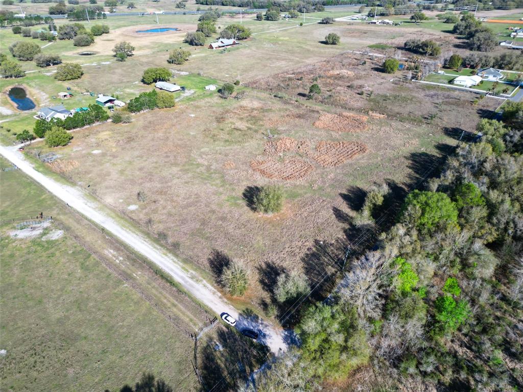 An aerial view shows a large, grassy, undeveloped plot of land with scattered trees — 000000- CR 614A, BUSHNELL, FL