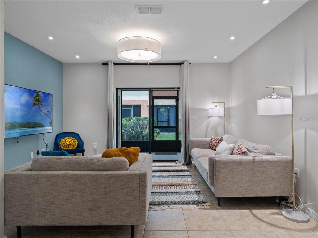 A living room features a blue accent wall, two sofas, a rug, and sliding glass doors — 2240 TRILLIUM PARK LANE, SANFORD, FL