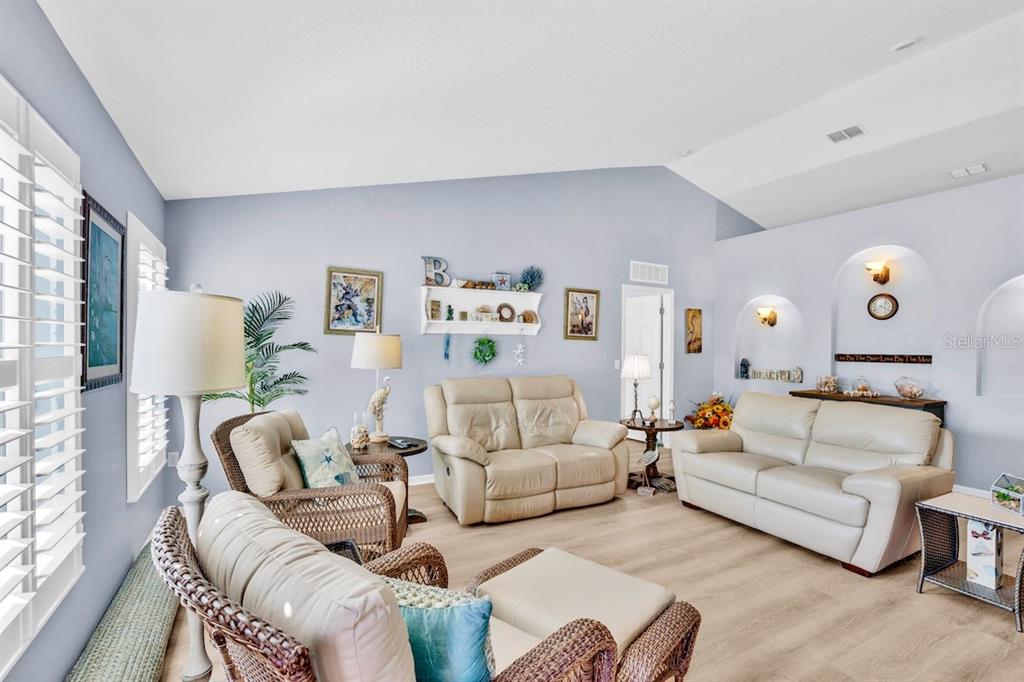 A living room features light blue walls, vaulted ceilings, wicker furniture, and a beige sofa — 1385 HAVERFORD LANE, SEBASTIAN, FL
