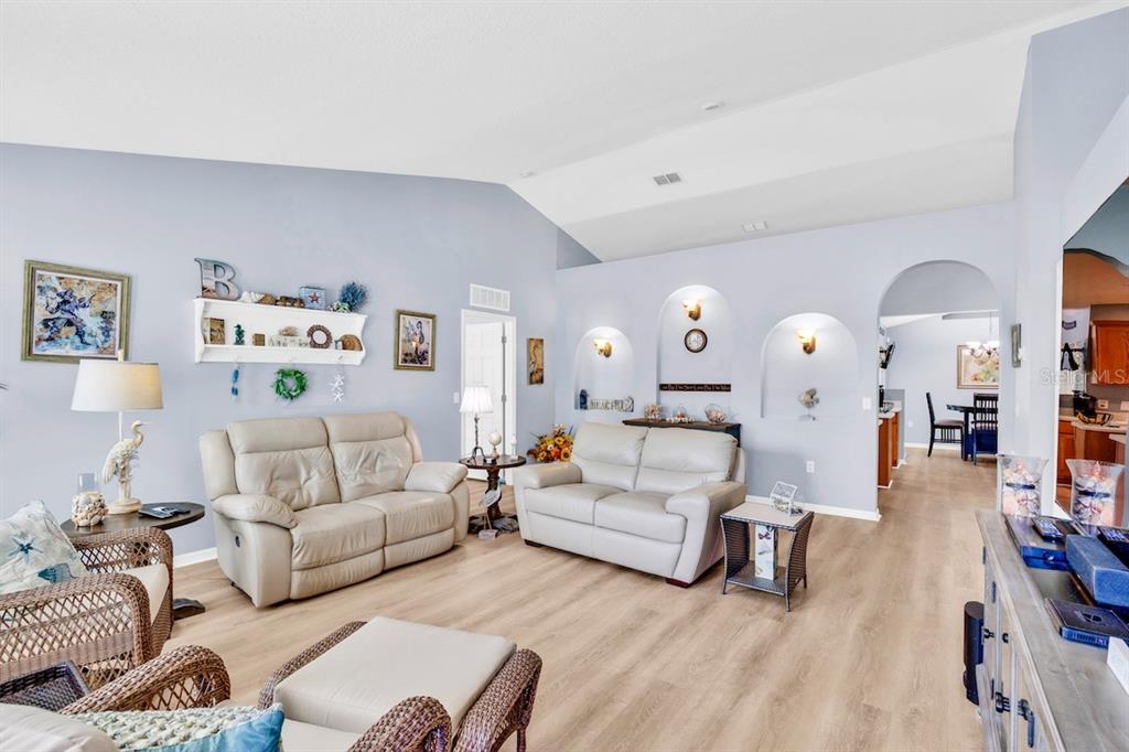A living room with light blue walls, vaulted ceilings, two leather sofas, and arched wall niches — 1385 HAVERFORD LANE, SEBASTIAN, FL
