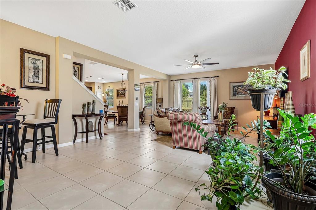 A spacious living and dining area features tile flooring, neutral walls, and large windows — 16700 ABBEY HILL COURT, CLERMONT, FL