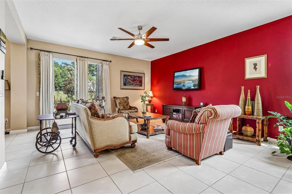 A living room features a red accent wall, tiled floors, and a sliding glass door — 16700 ABBEY HILL COURT, CLERMONT, FL