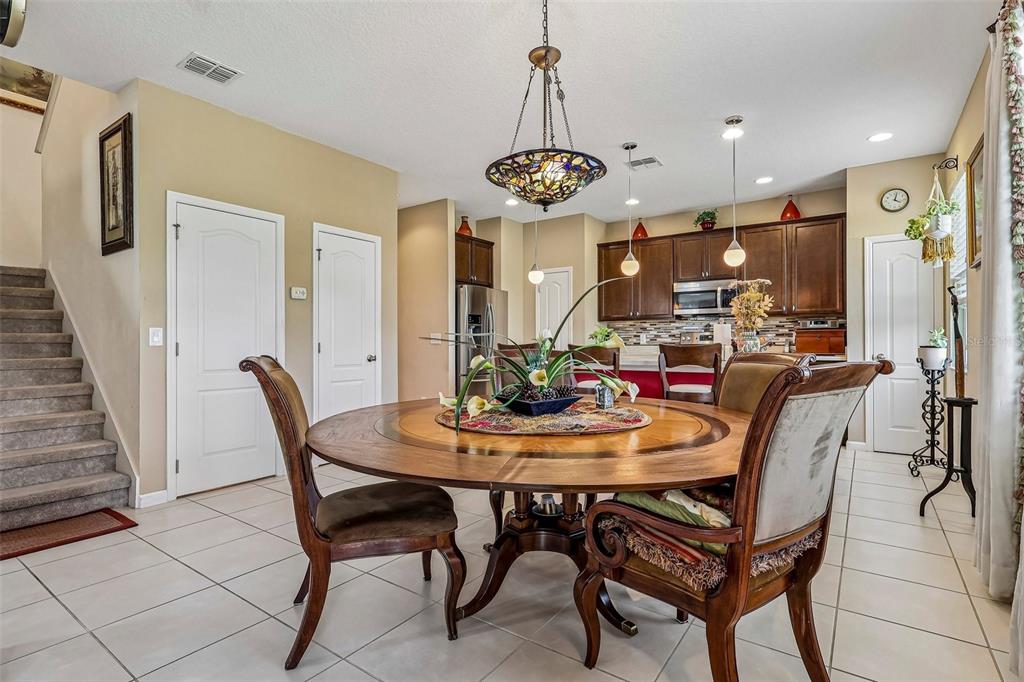A dining area with a round wooden table, chairs, and a stained-glass chandelier — 16700 ABBEY HILL COURT, CLERMONT, FL
