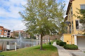 A view of a pond with a fountain next to apartment buildings and a sidewalk — 6121 METROWEST BOULEVARD UNIT 101, ORLANDO, FL
