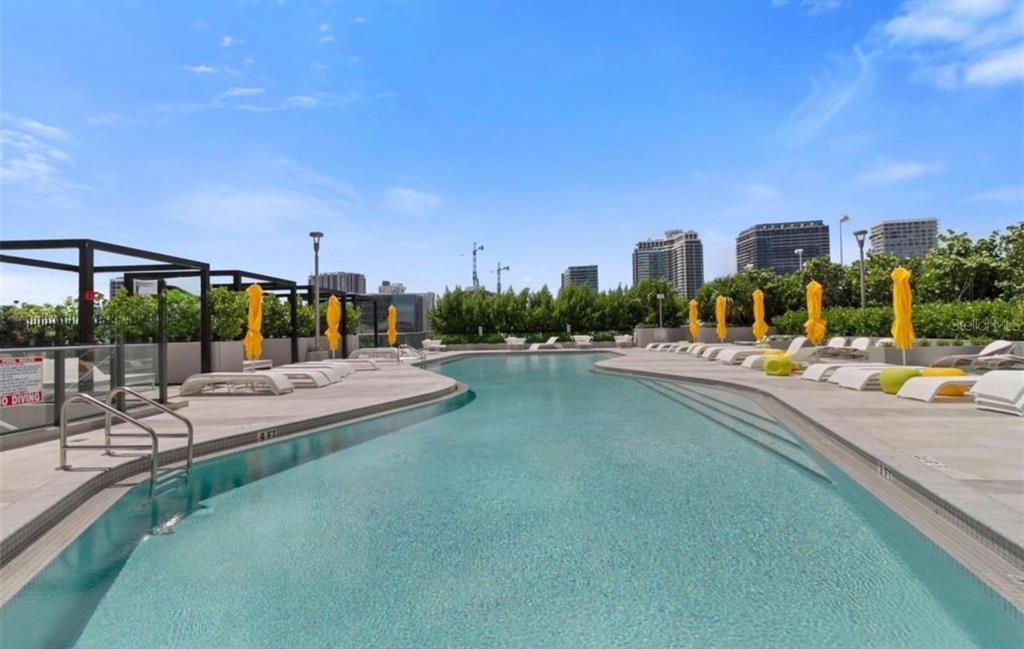 An outdoor swimming pool with lounge chairs and yellow umbrellas on a rooftop deck — 501 NE 31ST STREET UNIT 1808, MIAMI, FL