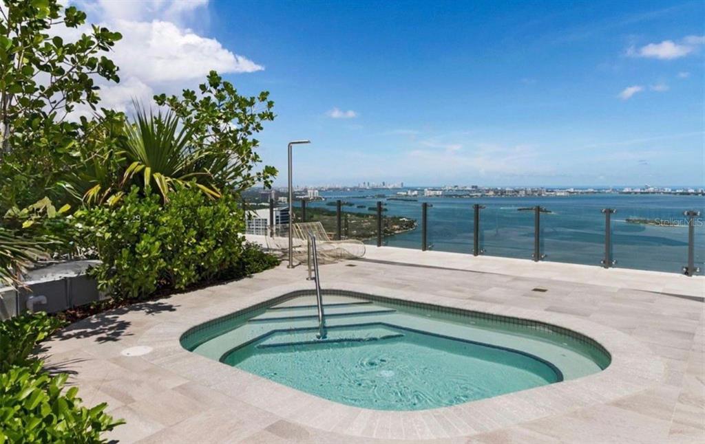 A rooftop hot tub sits on a tiled deck overlooking a bay and city skyline — 501 NE 31ST STREET UNIT 1808, MIAMI, FL