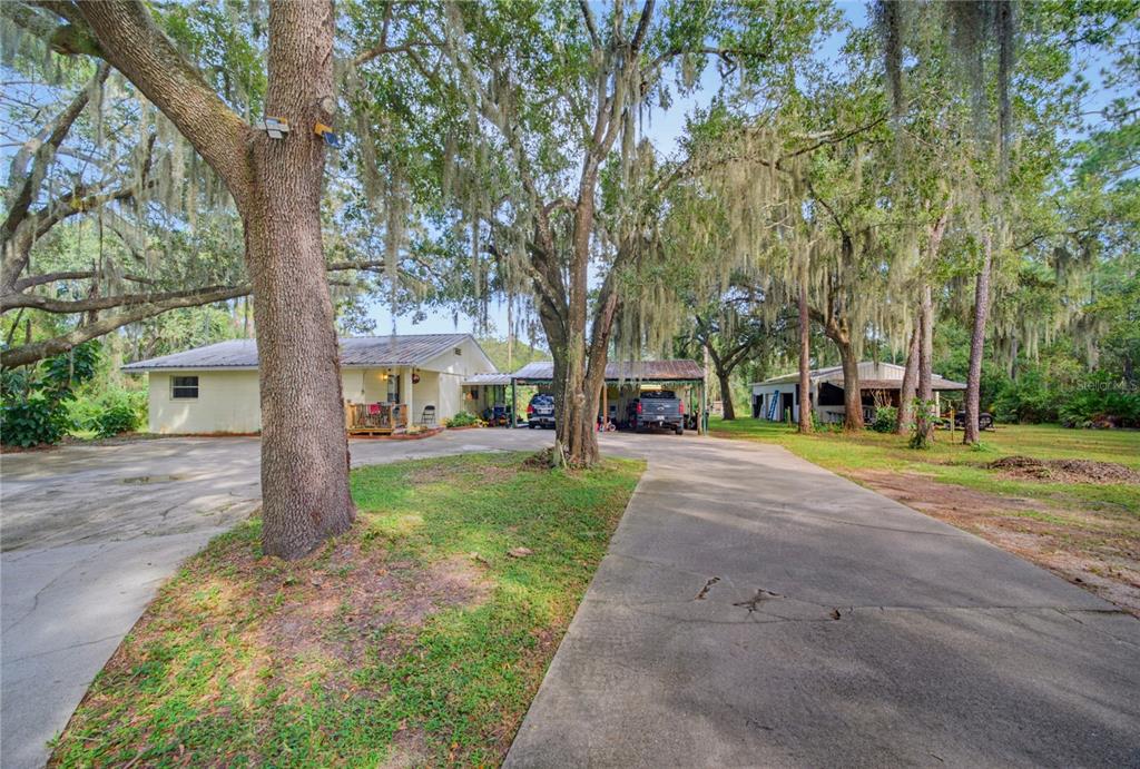 A single-story house with a metal roof, a carport, and a detached garage among trees — 10930 CAMP MACK ROAD, LAKE WALES, FL