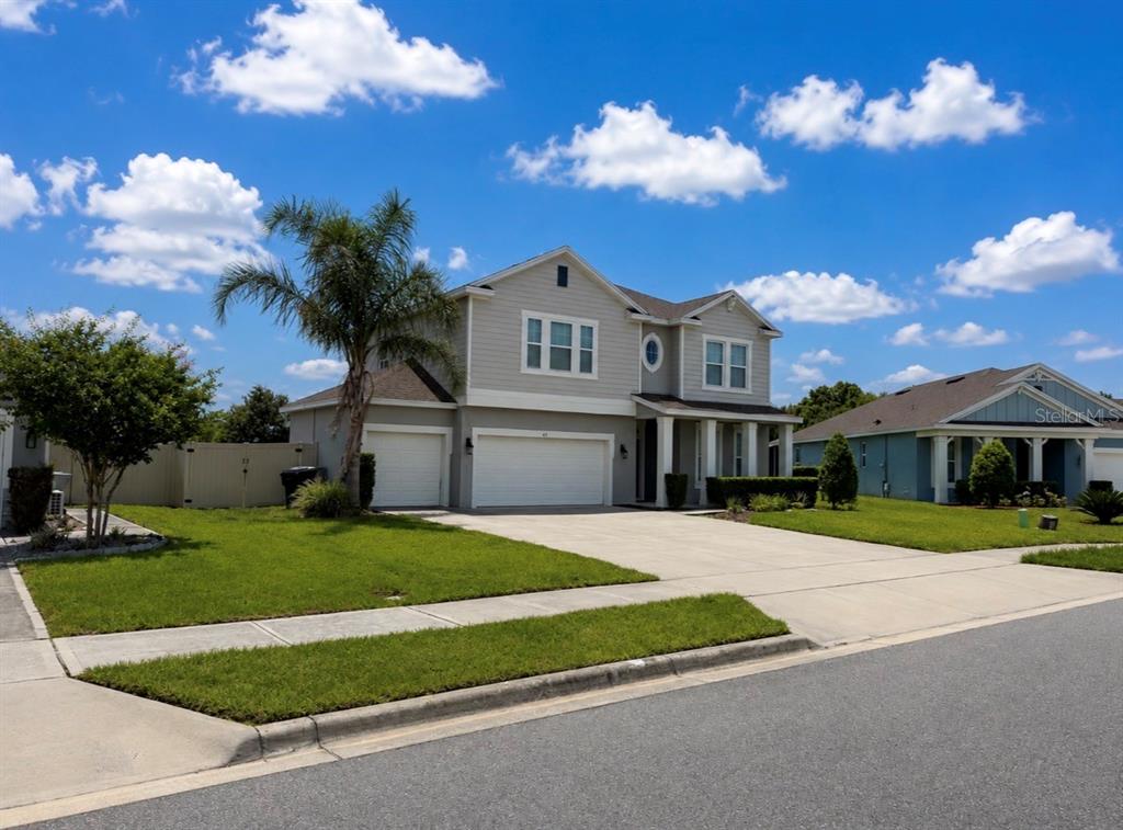 A two-story suburban house with a gray exterior, a three-car garage, and a palm tree — 431 HALTER DRIVE, APOPKA, FL