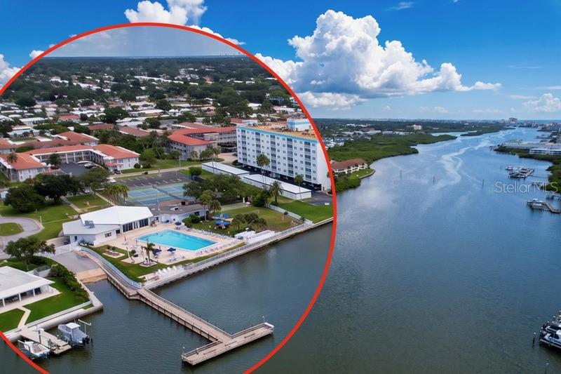 An aerial view shows a waterfront apartment complex with a pool, tennis courts, and dock — 10351 REGAL DRIVE UNIT 5, LARGO, FL