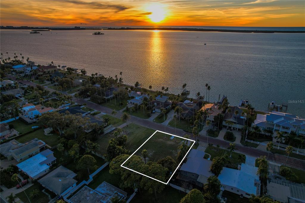 An aerial view shows a vacant, rectangular residential lot outlined in white near the water — 1645 SANTA BARBARA DRIVE, DUNEDIN, FL
