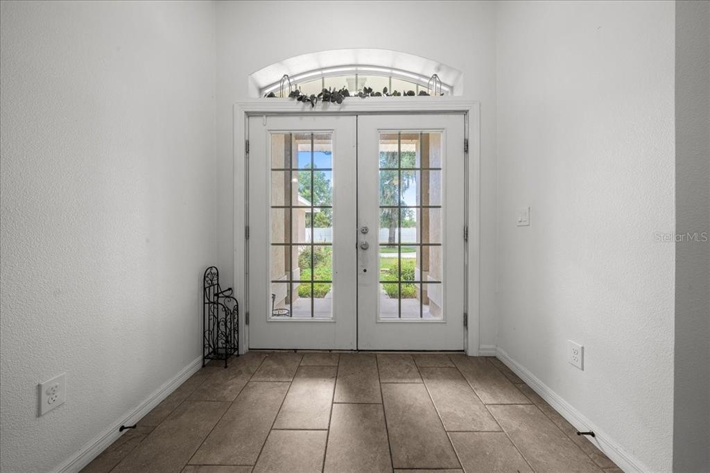 An entryway features tile flooring, white walls, and double glass doors with an arched transom window — 60 OWENS STREET, UMATILLA, FL