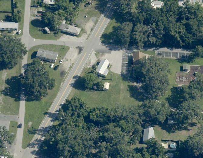 This aerial view shows a rural road intersection with several houses, parking lots, and trees — 821 S US 301, SUMTERVILLE, FL