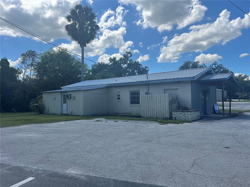 A single-story commercial building with a metal roof and a large paved parking lot — 821 S US 301, SUMTERVILLE, FL