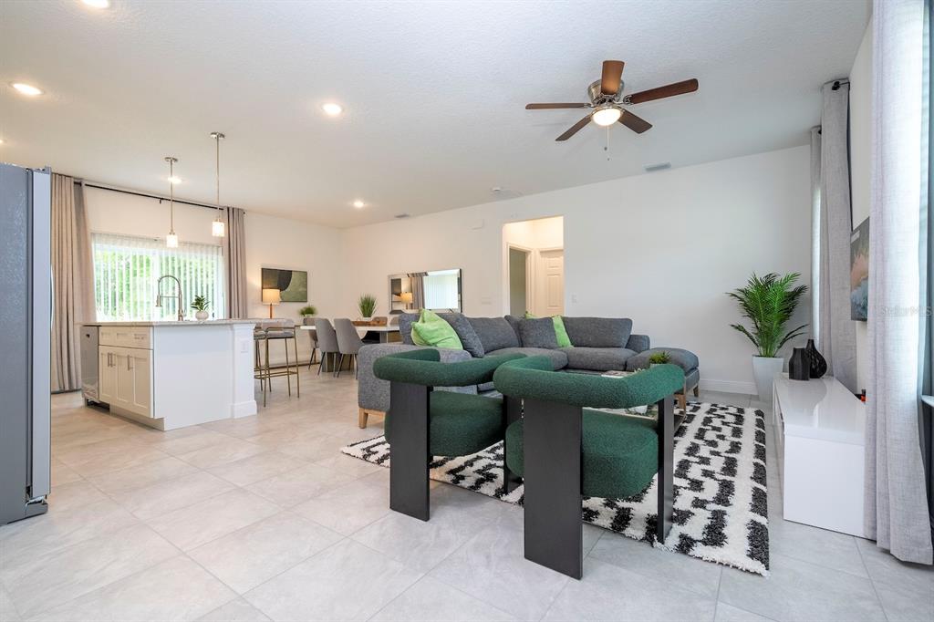 An open-concept living room and kitchen featuring gray tile floors, a sectional sofa, and chairs — 13825 SW 33RD COURT ROAD, OCALA, FL