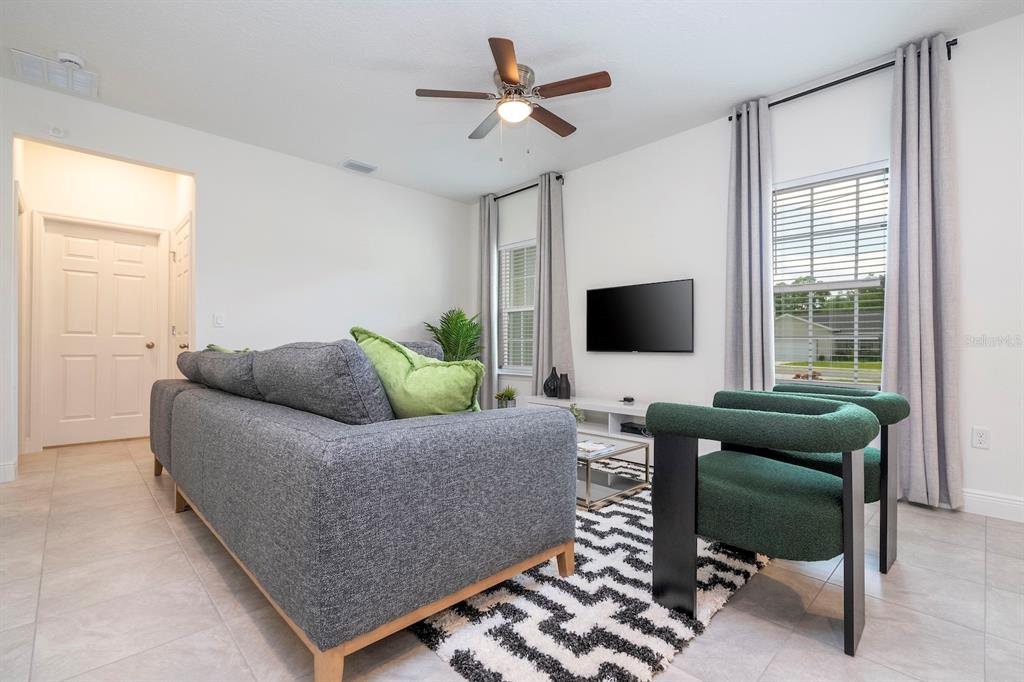 A living room features a grey sofa, two green armchairs, and a wall-mounted television — 13825 SW 33RD COURT ROAD, OCALA, FL