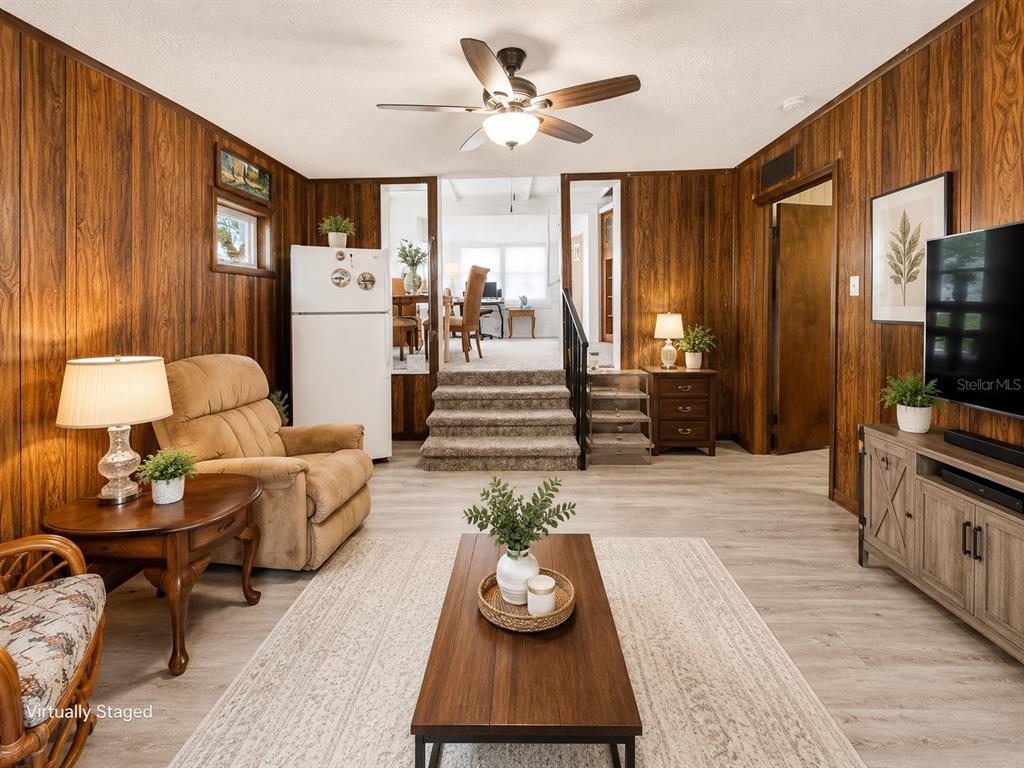 A living room features wood-paneled walls, light flooring, a ceiling fan, and steps leading upward — 3074 LARKIN ROAD, MIMS, FL