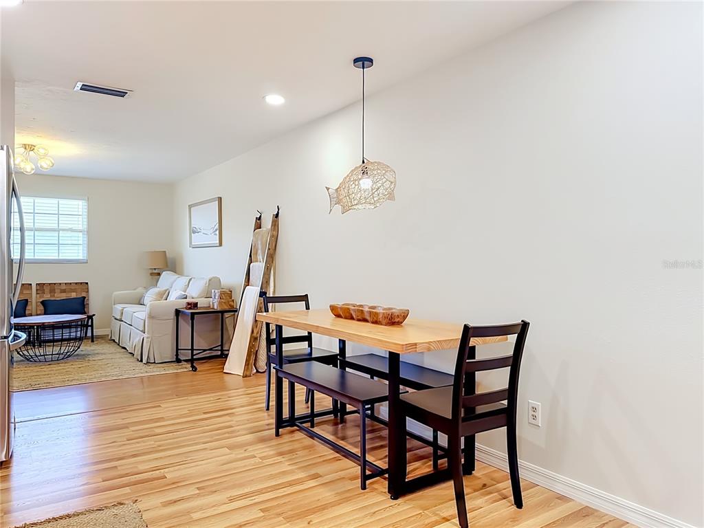A dining area with a wooden table and chairs sits adjacent to a living room — 202 PEACOCK LANE UNIT B, HOLMES BEACH, FL