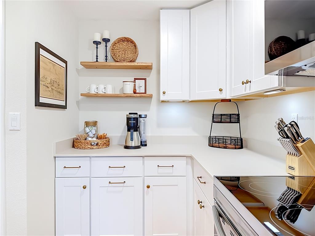 A kitchen corner features white cabinets, light countertops, open wooden shelving, and a coffee station — 202 PEACOCK LANE UNIT B, HOLMES BEACH, FL