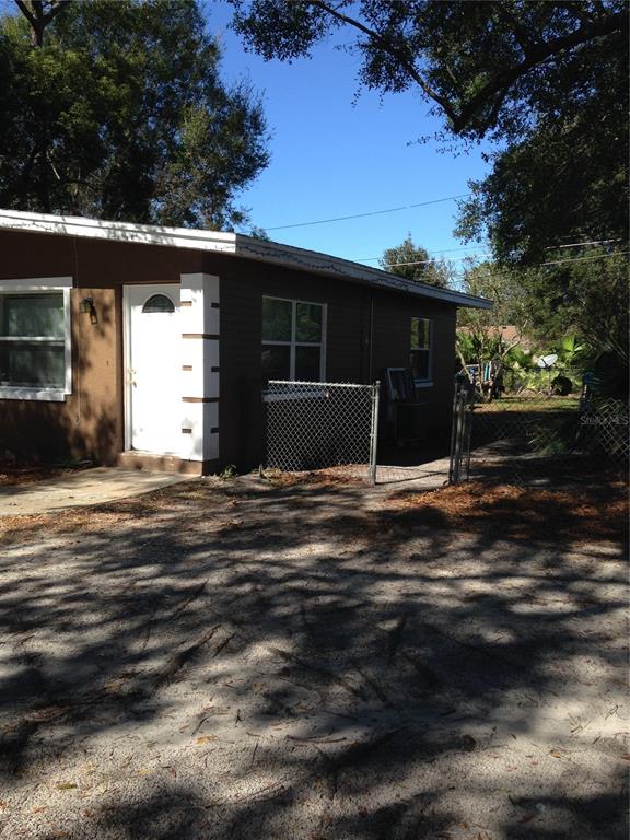 A brown exterior wall of a house features a white door and a chain-link fence — 2605 PEMBROOK DRIVE, ORLANDO, FL