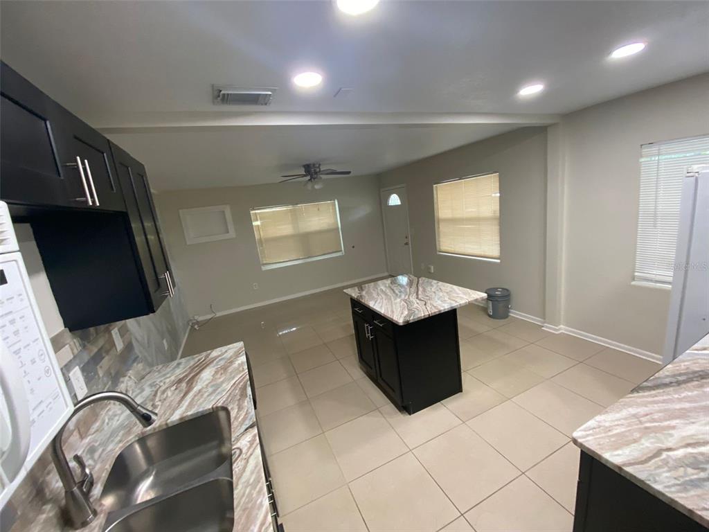 A kitchen features dark cabinets, stone countertops, a central island, and light-colored floor tiles — 2605 PEMBROOK DRIVE, ORLANDO, FL