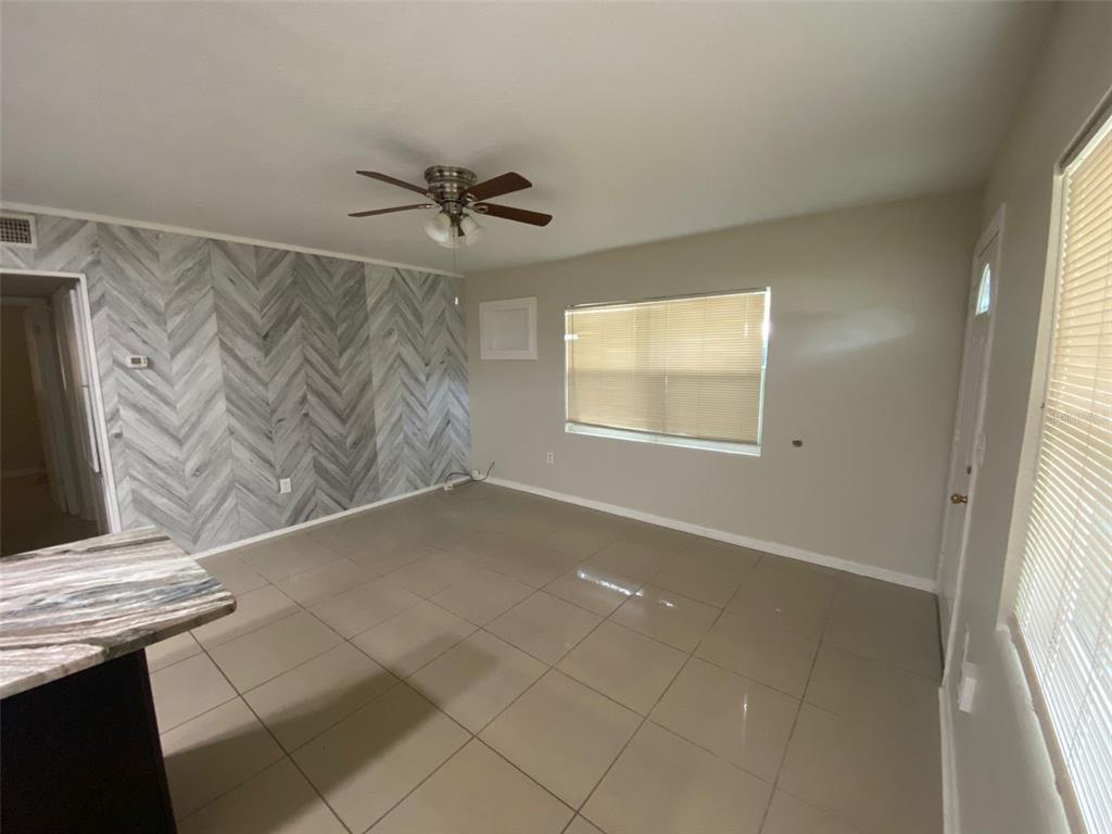 A room with large beige floor tiles, a herringbone-patterned accent wall, and a ceiling fan — 2605 PEMBROOK DRIVE, ORLANDO, FL
