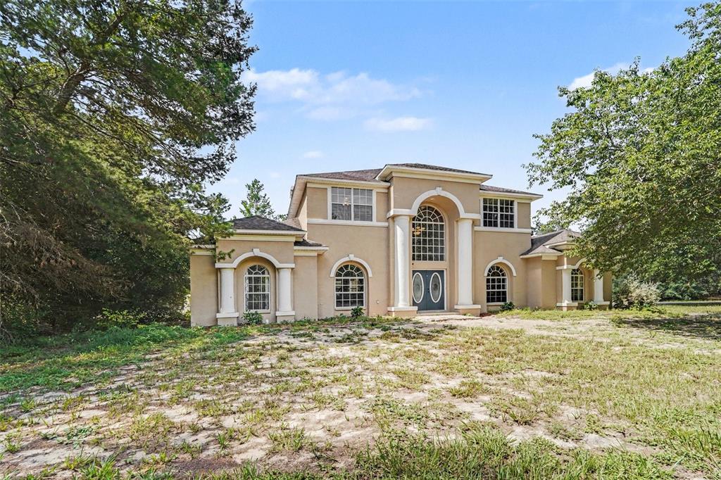 A two-story stucco house with a columned entryway and arched windows sits on a lot — 10724 PATRICK AVE, HUDSON, FL