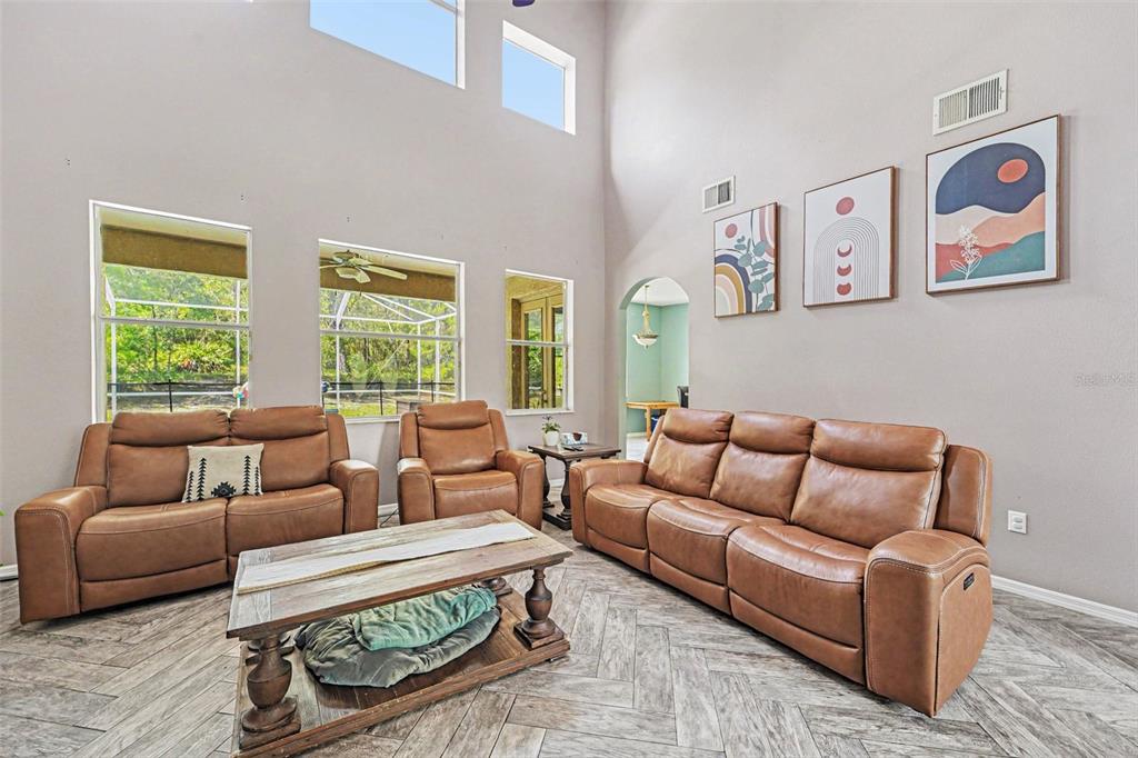 A living room features brown leather furniture, a wooden coffee table, and high ceilings — 10724 PATRICK AVE, HUDSON, FL