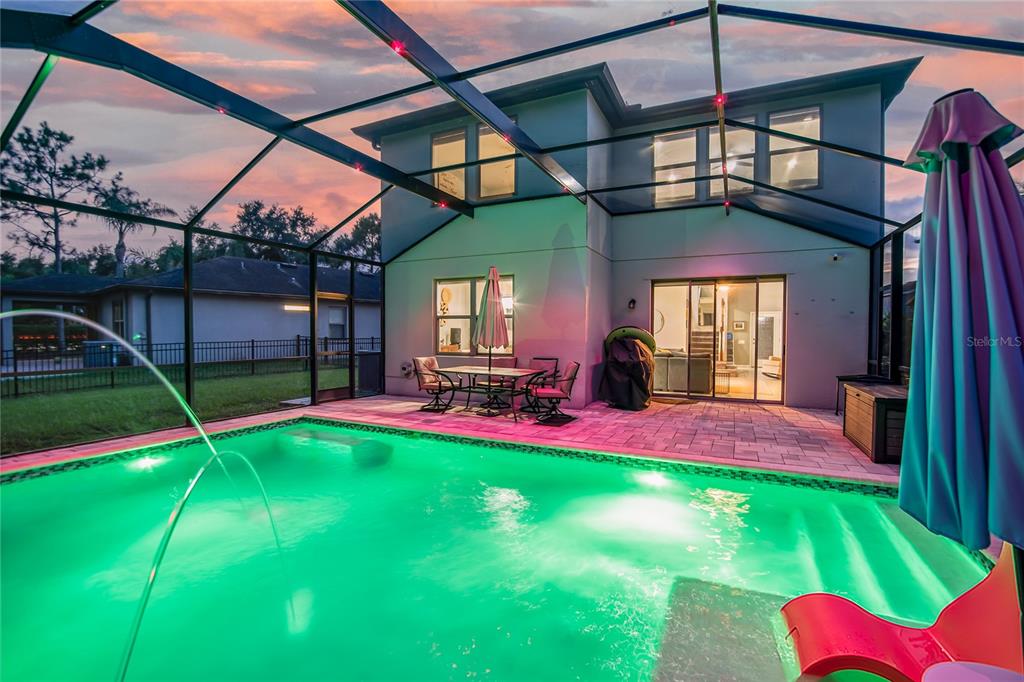A two-story house exterior features a screened-in patio with a swimming pool and dining furniture — 4346 O ROURKE COURT, WESLEY CHAPEL, FL