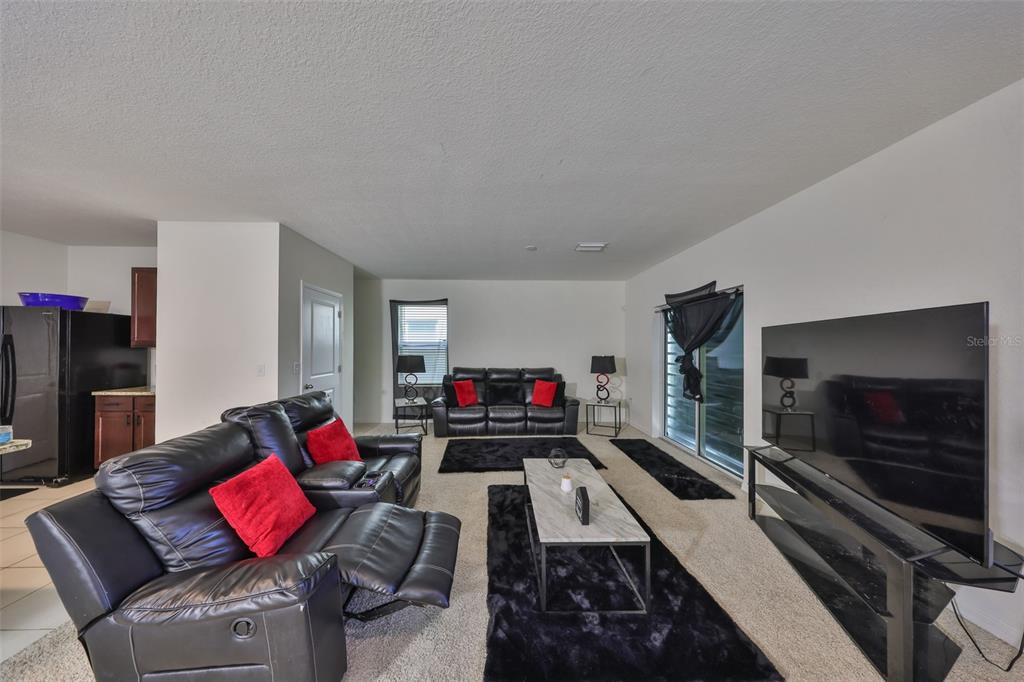 A living room features black leather sofas, a marble coffee table, and black area rugs — 10967 CARLTON FIELDS DRIVE, RIVERVIEW, FL