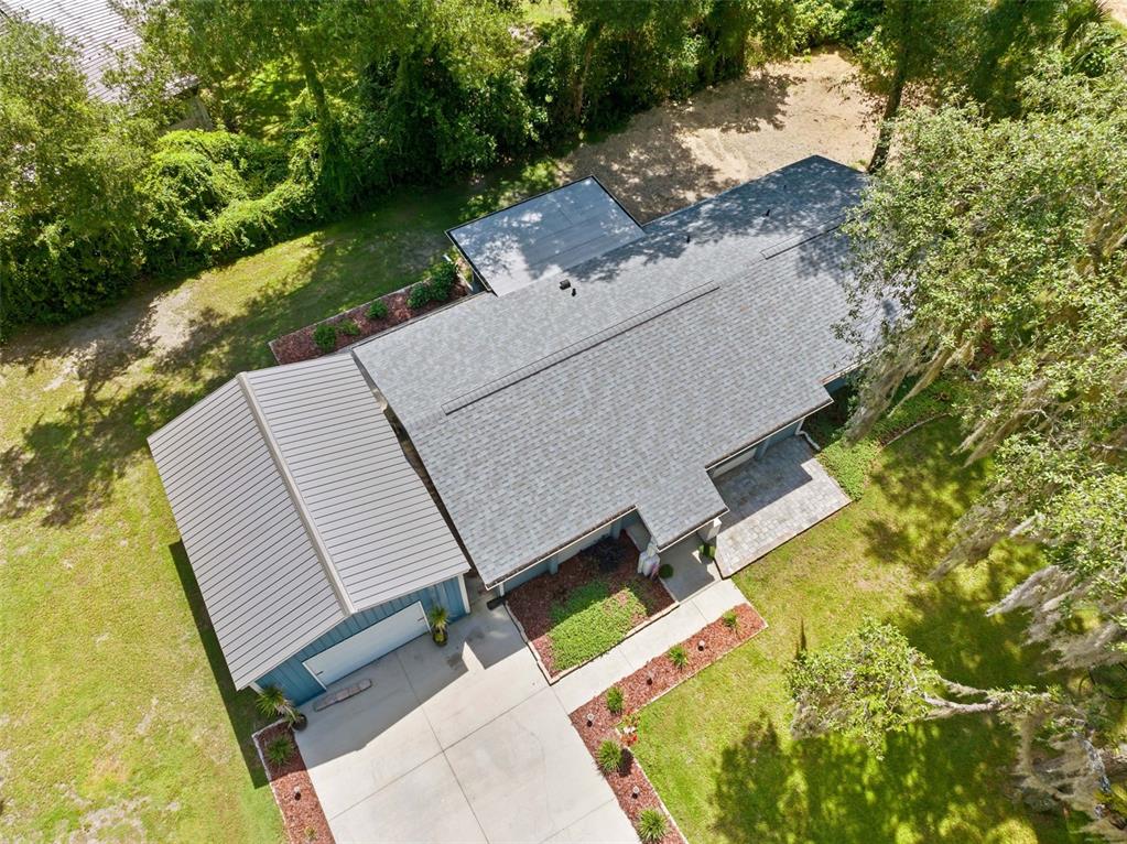 An aerial view shows a house with a shingled roof, metal-roofed garage, and paved driveway — 7625 S ANNIE TERRACE, FLORAL CITY, FL