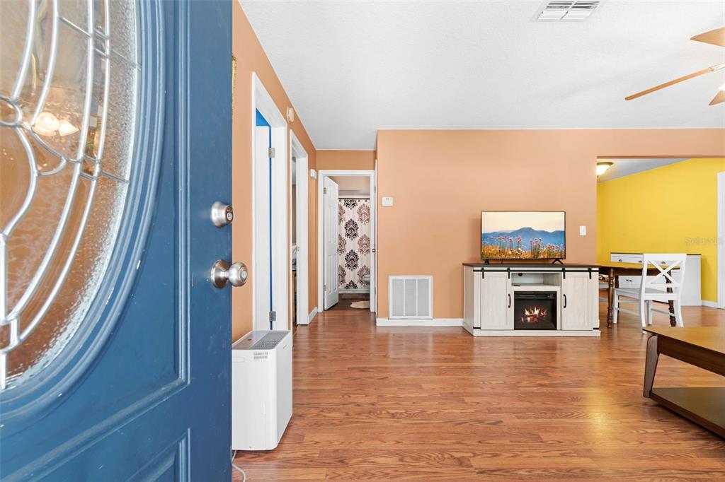 A view from an open blue front door into a living room with wood flooring — 7625 S ANNIE TERRACE, FLORAL CITY, FL