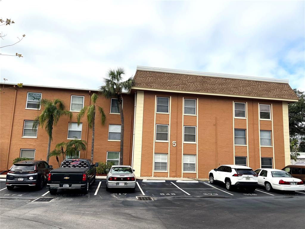 A three-story apartment building with a brown stucco exterior and a parking lot in front — 12760 INDIAN ROCKS ROAD UNIT 562, LARGO, FL