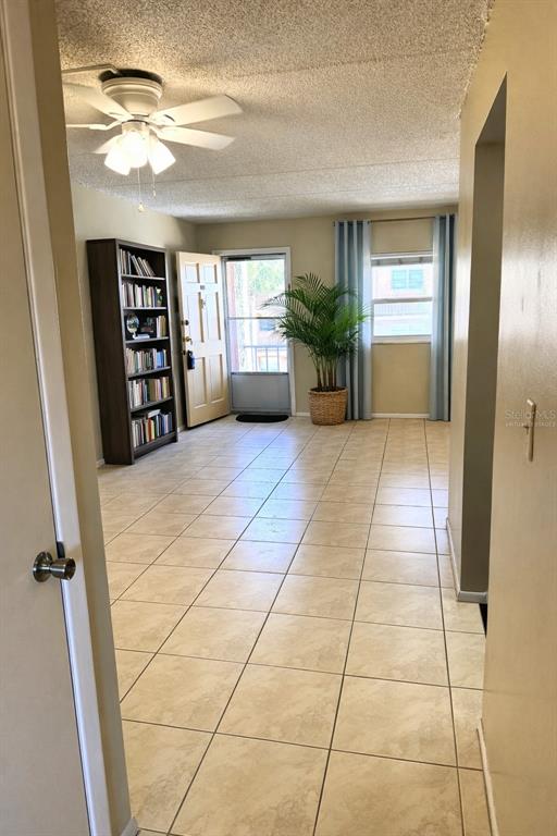 A room with beige tile flooring, a ceiling fan, a bookshelf, and a glass-paned door — 12760 INDIAN ROCKS ROAD UNIT 562, LARGO, FL