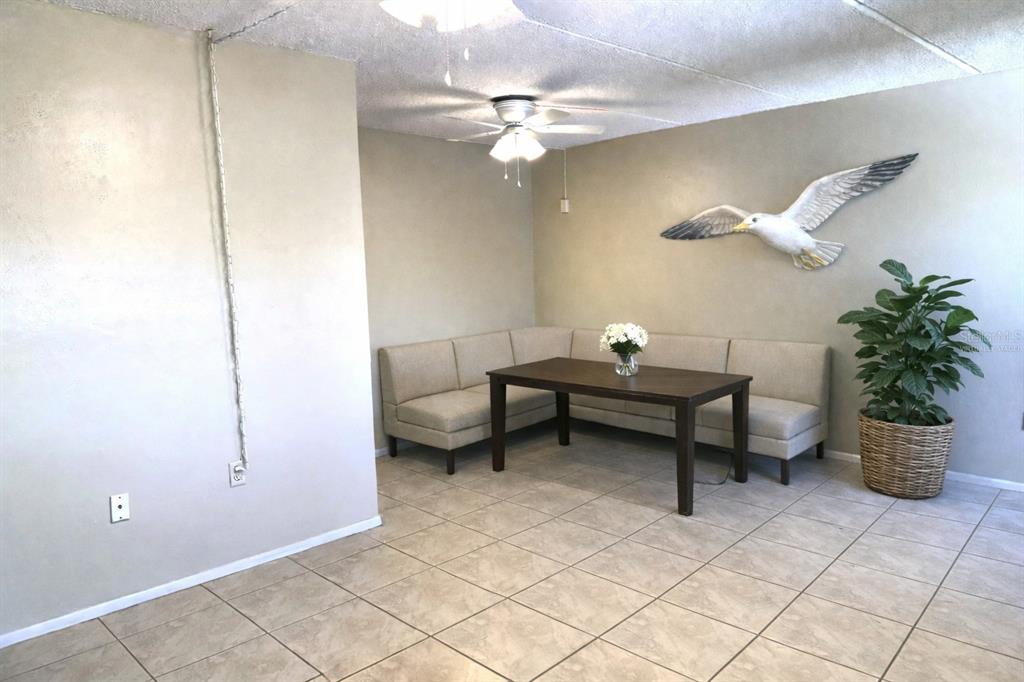 A dining area features a corner banquette, a wooden table, tile flooring, and a seagull wall decoration — 12760 INDIAN ROCKS ROAD UNIT 562, LARGO, FL