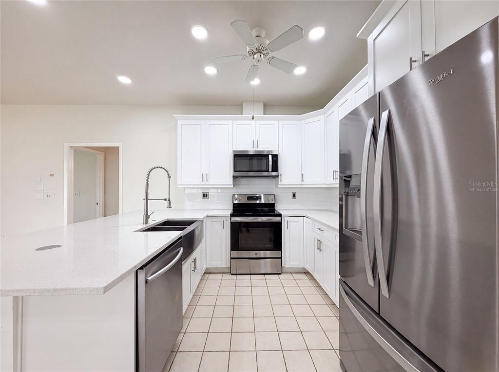 A kitchen with white cabinets, stainless steel appliances, a large island, and tiled flooring — 12919 PRESTWICK DRIVE, RIVERVIEW, FL