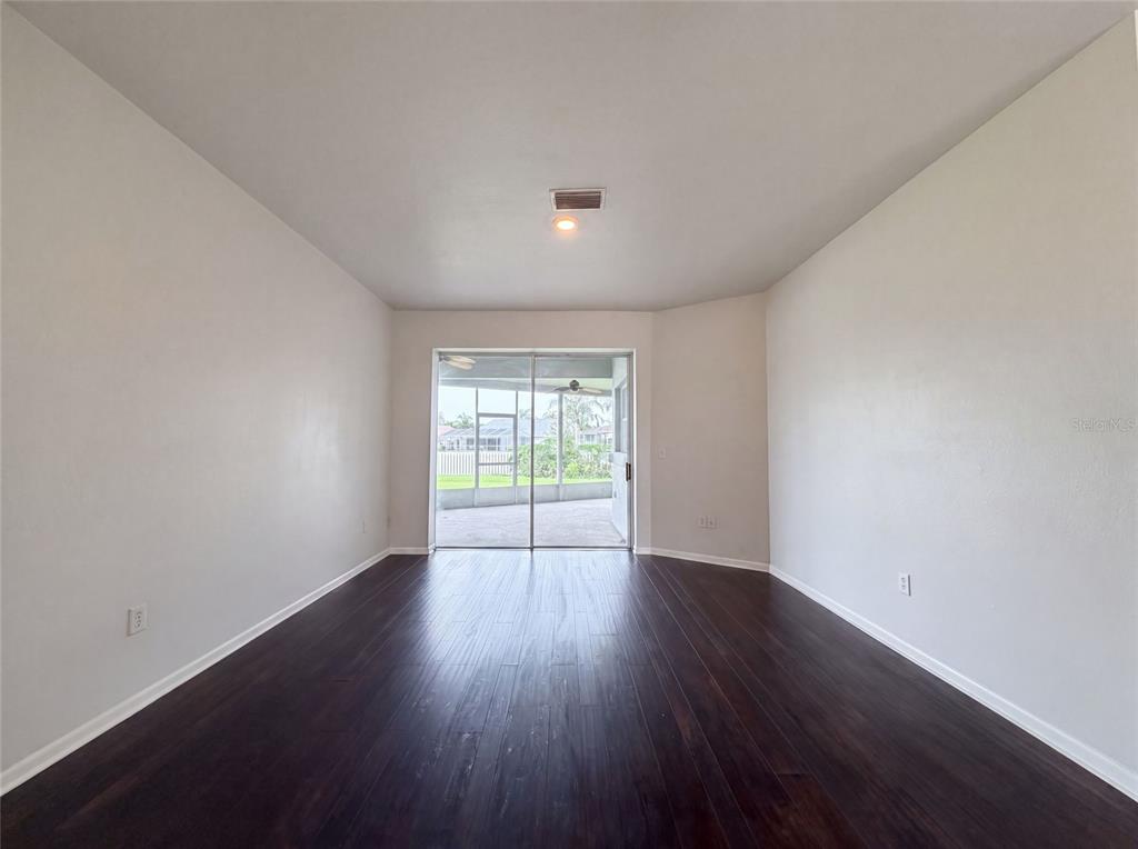 An empty room with dark wood-look flooring, white walls, and a sliding glass door — 12919 PRESTWICK DRIVE, RIVERVIEW, FL