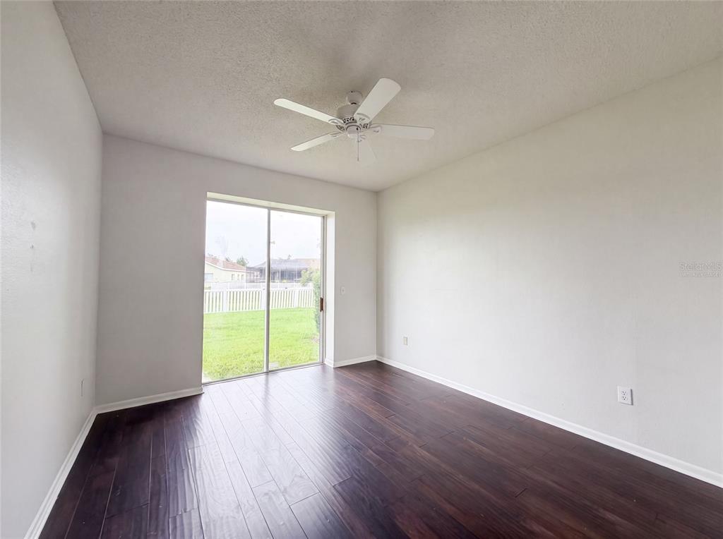 An empty room with dark wood flooring, a ceiling fan, and sliding glass doors — 12919 PRESTWICK DRIVE, RIVERVIEW, FL