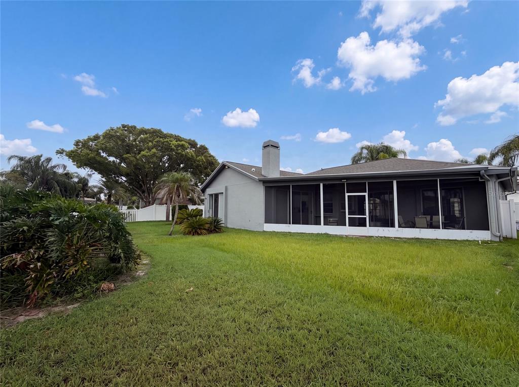 A view of the backyard featuring a gray house with a screened-in patio and chimney — 12919 PRESTWICK DRIVE, RIVERVIEW, FL