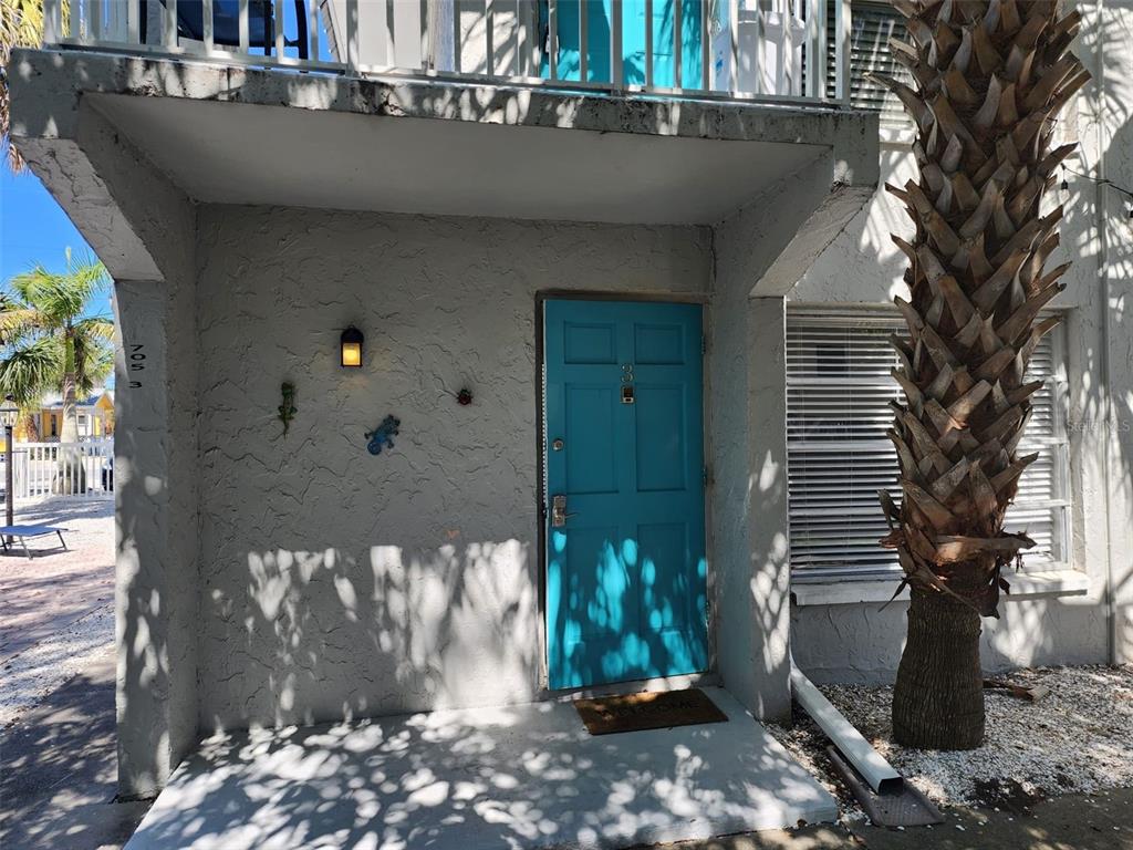 A gray two-story building features a bright blue door and a palm tree out front — 705 1ST STREET UNIT 3, INDIAN ROCKS BEACH, FL