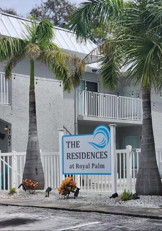 An exterior view of a building entrance featuring a bright blue door and a palm tree — 705 1ST STREET UNIT 3, INDIAN ROCKS BEACH, FL