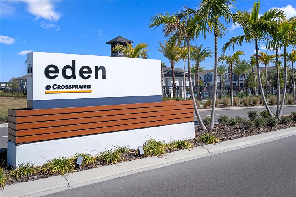 A white monument sign for Eden at Crossprairie stands near a road with palm trees — 5002 RAIN SHADOW DRIVE, ST CLOUD, FL