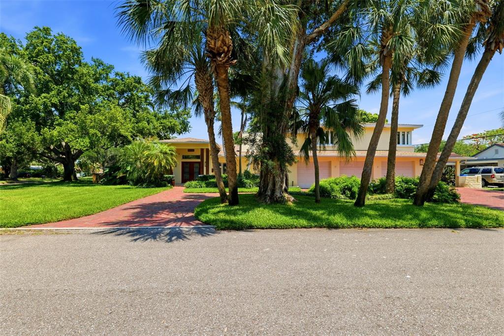 A multi-story house with a three-car garage and a brick driveway surrounded by palm trees — 6000 2ND STREET S, ST PETERSBURG, FL