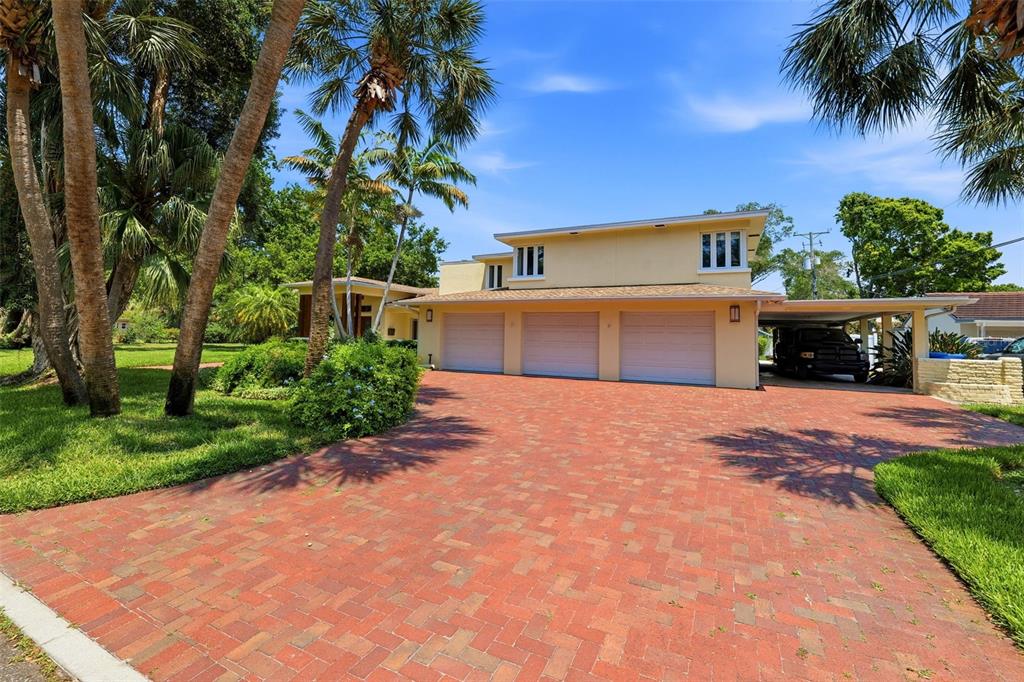 A three-car garage and carport are attached to a two-story house with a brick driveway — 6000 2ND STREET S, ST PETERSBURG, FL