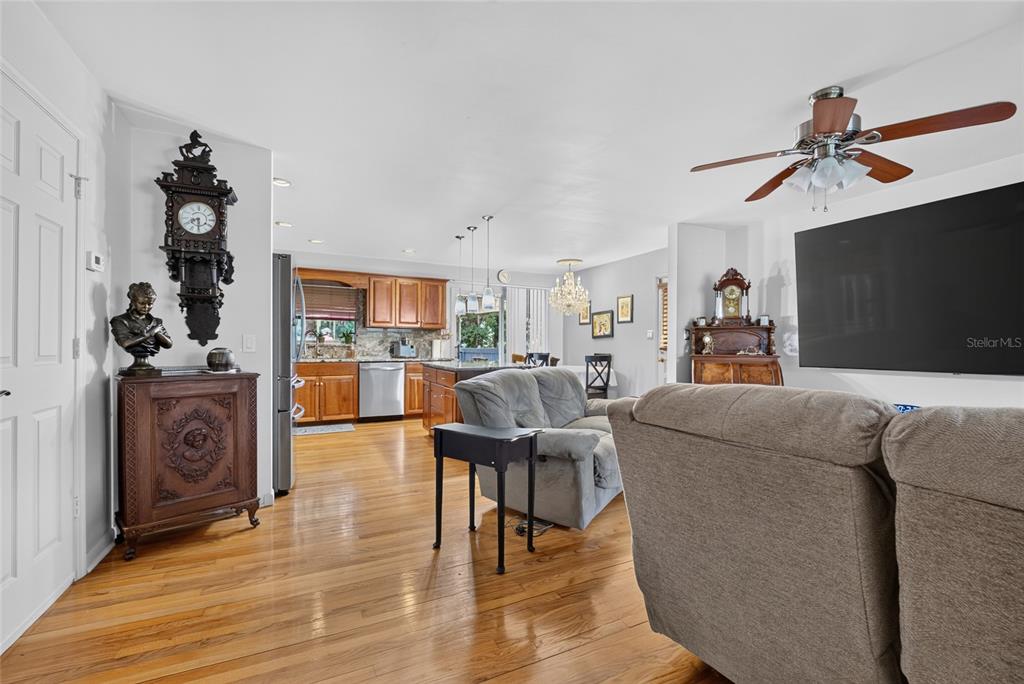 An open-concept living room and kitchen featuring hardwood floors, wooden cabinetry, and a ceiling fan — 602 SE 19TH STREET, OCALA, FL