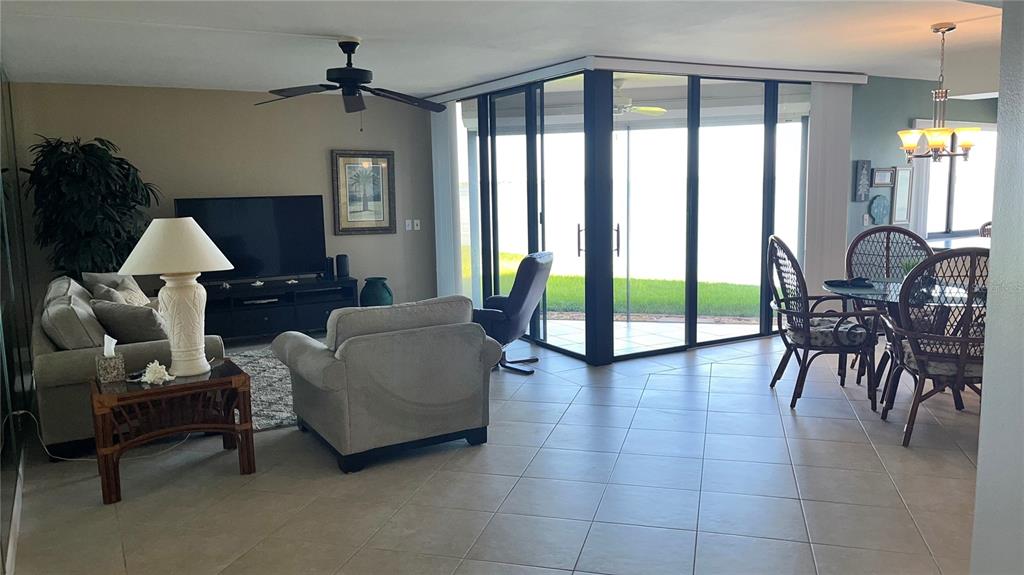 A living and dining area features tile floors, a ceiling fan, and large glass sliding doors — 5541 PUERTA DEL SOL BOULEVARD S UNIT 118, ST PETERSBURG, FL